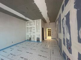Bautenstand 07.04.2026: Auf der Baustelle sind in den vergangenen Wochen erneut deutliche Fortschritte erzielt worden. Die wesentlichen Rohbauarbeiten sind bereits abgeschlossen – das Gebäude ist vollständig errichtet und durch den Einbau von Fenstern und Haustüren nun klar in seiner finalen Kubatur erkennbar. Im Bereich Dach konnten die vorbereitenden Maßnahmen erfolgreich fertiggestellt werden. Der Fokus liegt derzeit auf der Abdichtung des Hauptdachs, die planmäßig umgesetzt wird. Auch der technische Ausbau entwickelt sich kontinuierlich weiter: Die Elektroinstallation sowie die Gewerke Heizung, Sanitär und Lüftung befinden sich in einem fortgeschrittenen Stadium und werden aktuell in den oberen Etagen weitergeführt. Der Innenausbau nimmt ebenfalls zunehmend Gestalt an. Große Teile des Trockenbaus sind bereits realisiert, einzelne Wandbereiche geschlossen. Die Kellerdämmung befindet sich in den letzten Zügen, und die Montage der Stahlzargen ist abgeschlossen. Die Estricharbeiten wurden im Kellergeschoss erfolgreich beendet und schreiten im Erdgeschoss weiter voran. Parallel dazu haben die Fassadenarbeiten begonnen, sodass sich auch das äußere Erscheinungsbild des Gebäudes weiterentwickelt. Fazit: Der Baufortschritt verläuft weiterhin stabil und im vorgesehenen Zeitrahmen.