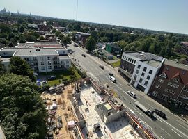 14.08.2025:  Auf der Baustelle sind die Arbeiten am Erdgeschoss in unterschiedlichen Bauabschnitten fortgeschritten.   Im ersten Bauabschnitt wurde die Bodenplatte bereits vollständig hergestellt, und die Betonarbeiten für die tragenden Wände im Erdgeschoss haben begonnen. Erste Wände und Schächte sind betoniert, die Schalungs- und Bewehrungsarbeiten für weitere Wandabschnitte laufen. Das Arbeitsumfeld ist eingerichtet, Material liegt geordnet bereit, und Gerüste an den Außenkanten sichern die laufenden Arbeiten.   Im zweiten Bauabschnitt ist der Rohbau des Erdgeschosses bereits vollständig fertiggestellt. Sämtliche tragenden Wände sind errichtet, und die Baustelle hat nahtlos mit den Rohbauarbeiten im 1. Obergeschoss begonnen. Hier werden aktuell die ersten tragenden Wände des 1. Obergeschosses gestellt, während gleichzeitig vorbereitende Maßnahmen für die das 2.Obergeschoss getroffen werden.